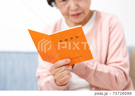 年金手帳を持つシニア女性　不安 73726099