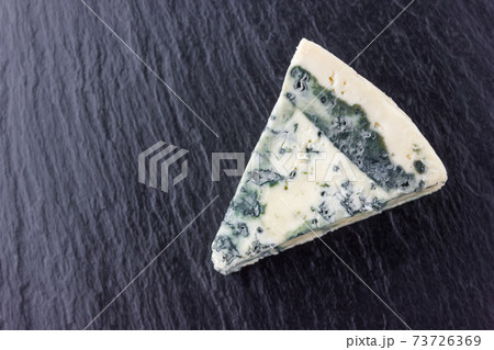 Cheese with mold on a board of stone. Gorgonzola cheese close-up on a surface of slate. Cheese with mold on a board of stone. Gorgonzola cheese close-up on a surface of slate. 73726369