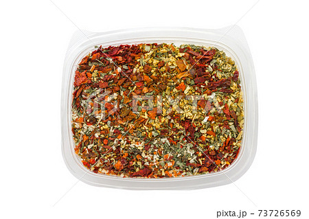 Dry seasoning in a plastic container. Different condiments in a container on a white background. Dry seasoning in a plastic container. Different condiments in a container on a white background. 73726569