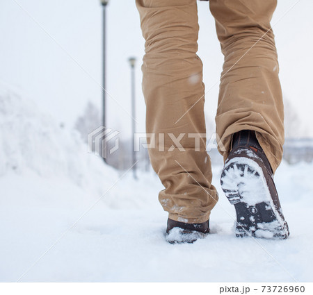 A person is walking on a slippery road, the first snow in the park A person is walking on a slippery road, the first snow in the park 73726960