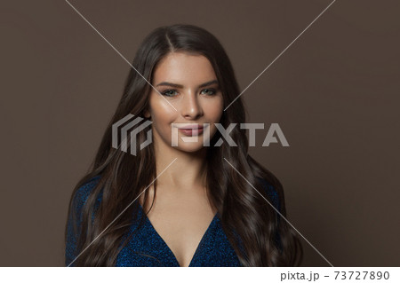 Attractive woman face with clear skin, long curly hair and natural makeup on brown background 73727890