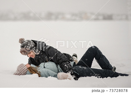 Loving guy and girl are lying in the snow. Young happy couple walking in winter Loving guy and girl are lying in the snow. Young happy couple walking in winter 73728078