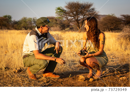 Guide squatting in grassland makes brunette laugh Guide squatting in grassland makes brunette laugh 73729349