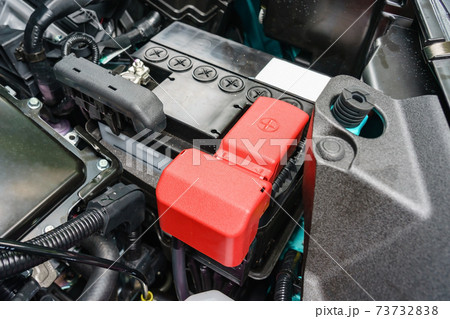 close-up on new small eco car battery installed in the compartment showing good arrangement and safety, clear communicated design of electrical connector and warning pictogram signs on the top cover close-up on new small eco car battery installed in the compartment showing good arrangement and safety, clear communicated design of electrical connector and warning pictogram signs on the top cover 73732838