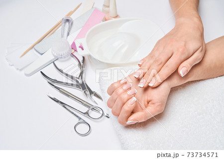Beautiful Female Hands with French manicure over light grey background Beautiful Female Hands with French manicure over light grey background 73734571