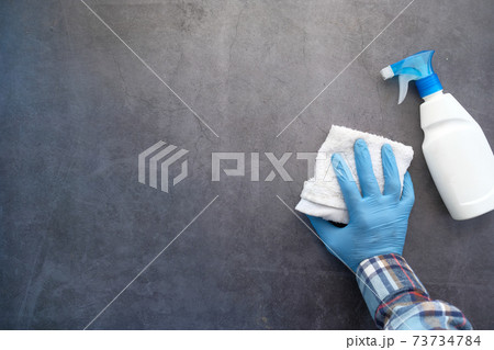 hand in blue rubber gloves cleaning table with cloth  73734784