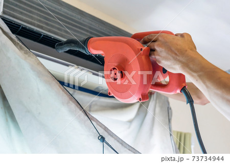 Service technician is cleaning, repair and maintenance of air conditioner 73734944