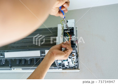 Technician repairing air conditioner with screwdriver, installation electric wires of the air conditioner 73734947