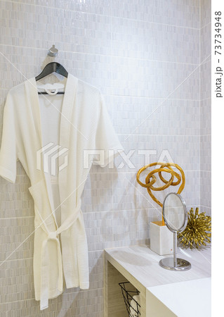 White bathrobe decoration on a hanger in bathroom interior 73734948