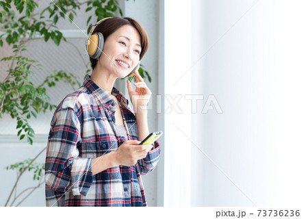 室内でスマホの音楽配信アプリの音楽をヘッドフォンで楽しむ女性 73736236