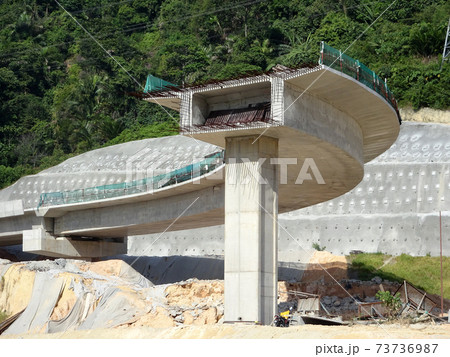 PENANG, MALAYSIA - MARCH 21, 2020: Overhead road under construction. The massive concrete column used to support the concrete road deck. Construction work is in full swing. PENANG, MALAYSIA - MARCH 21, 2020: Overhead road under construction. The massive concrete column used to support the concrete road deck. Construction work is in full swing. 73736987