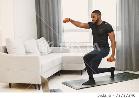 Handsome Afro American sportsman working out at home Handsome Afro American sportsman working out at home 73737240