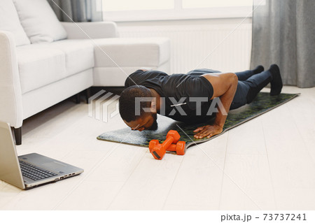 Handsome Afro American sportsman working out at home Handsome Afro American sportsman working out at home 73737241