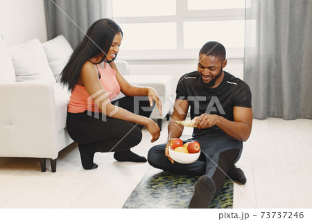 Handsome Afro American couple sitting with fruitsat home Handsome Afro American couple sitting with fruitsat home 73737246
