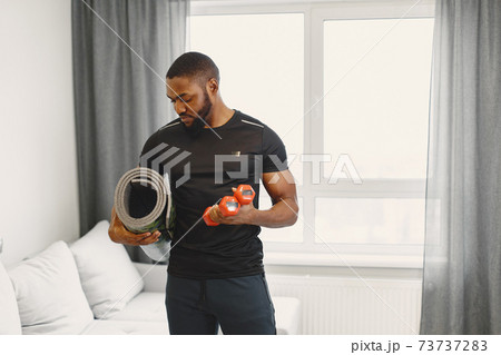 Handsome Afro American sportsman working out at home Handsome Afro American sportsman working out at home 73737283