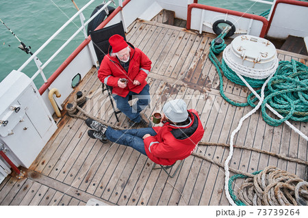 Fishermans sitting at the deck of the boat and having conversation Fishermans sitting at the deck of the boat and having conversation 73739264