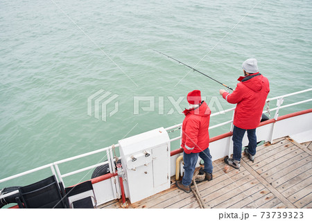 Sailor helping to the diligent fisher to taking out fish from sea 73739323
