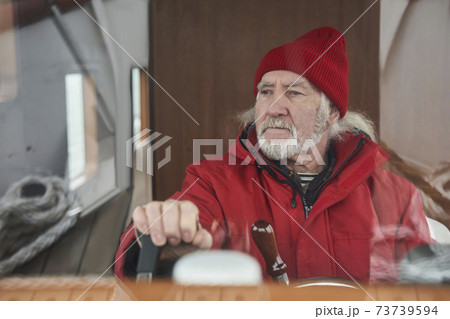 Sailor man standing at the steering wheel and floating at the yacht Sailor man standing at the steering wheel and floating at the yacht 73739594