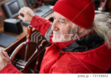 Yacht skipper standing at the steering wheel 73739602