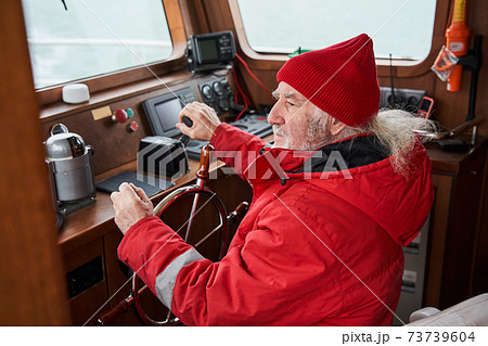 Man holding hands on steering wheel and navigating sailboat 73739604