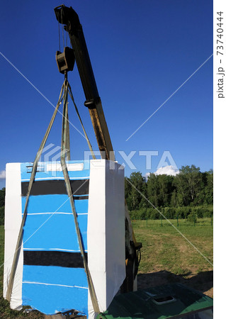 The mobile crane unloads pallets of blocks from the trailer of the truck. 73740444