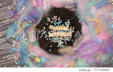 Colorful Easter eggs in bird nest surrounded with pastel colored feathers and wooden cubes with the text Happy Easter top view, modern background design, Easter holliday, Spring, concept Colorful Easter eggs in bird nest surrounded with pastel colored feathers and wooden cubes with the text Happy Easter top view, modern background design, Easter holliday, Spring, concept 73740687
