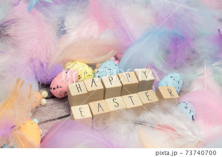 Happy Easter written with wooden cubes surrounded with beautiful pastel colored decorative feathers and eggs, April, Easter, Religion, Spring concept for background and greeting card top view Happy Easter written with wooden cubes surrounded with beautiful pastel colored decorative feathers and eggs, April, Easter, Religion, Spring concept for background and greeting card top view 73740700