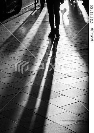 Long human shadows projected on the pavement at sunset 73741436