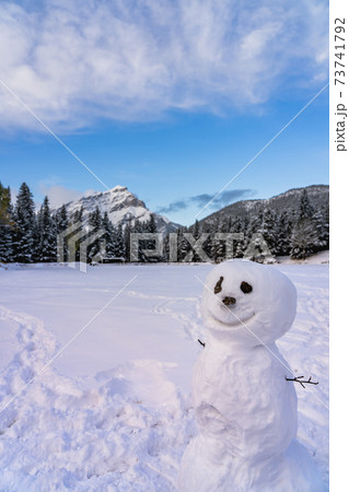 A smiling snowman in the snowy playground. Cascade Mountain and trees in the background. Banff National Park, Canadian Rockies. 73741792