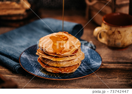 Women stream delicious mapple syrup for home made american pancakes Women stream delicious mapple syrup for home made american pancakes 73742447