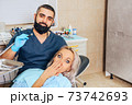 A frightened blonde girl at a reception at a cheerful dentist. 73742693