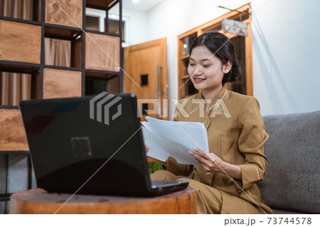 woman civil servant working from home using laptop computer and worksheets sitting woman civil servant working from home using laptop computer and worksheets sitting 73744578