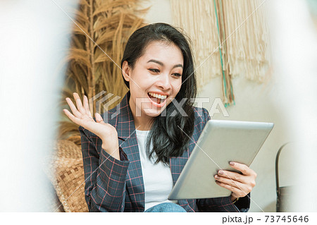 a happy beautiful woman in a blazer uses a digital tablet 73745646