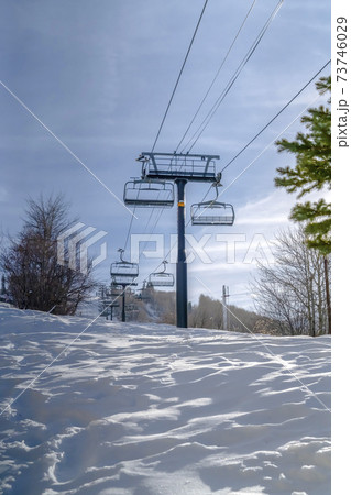 Sunlit snow under ski lifts and peaceful blue sky 73746029