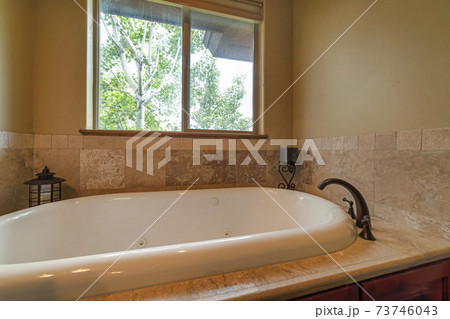 Interior view of a bathroom with close up of the gleaming bathtub and faucet 73746043