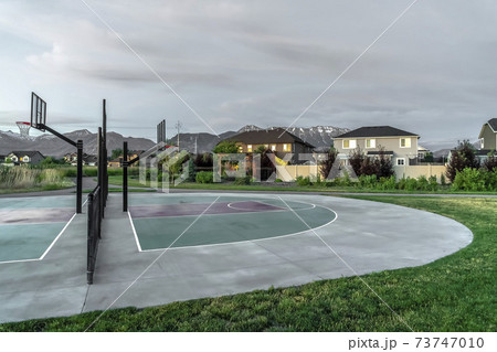 Back to back half basketball courts with homes and towering mountain background Back to back half basketball courts with homes and towering mountain background 73747010