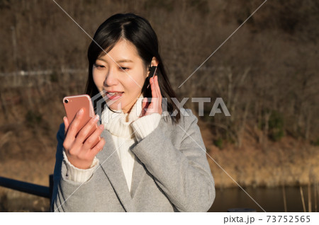 夕暮れにスマホでビデオ通話をする女性 73752565