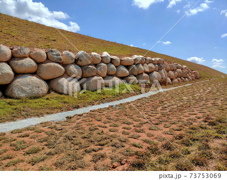 Natural boulders are used as retaining walls of ground banks that have been embanked. Other slopes are planted with grass to prevent erosion caused by rain. 73753069