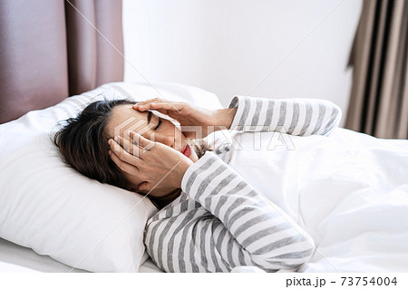 Young asian woman suffering from head ache in the bedroom after wake up in the morning Young asian woman suffering from head ache in the bedroom after wake up in the morning 73754004