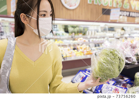 スーパーで買い物をするマスク姿の女性買い物客の写真素材