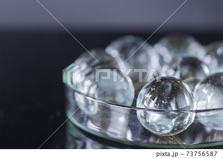 黒を背景に透明な皿の中に入ったガラス球の写真素材