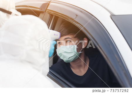 Asian Woman Drive Thru Covid-19 Testing With PPE Medical Staff, COVID testing temp while checking in cars Asian Woman Drive Thru Covid-19 Testing With PPE Medical Staff, COVID testing temp while checking in cars 73757292