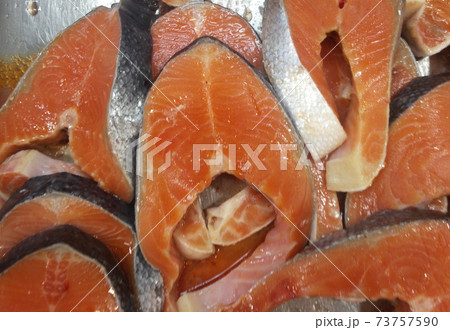 Salmon meat and head was cut into pieces for sale. Available on the metal tray at the market. 73757590