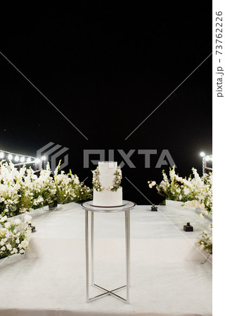 wedding white cake on a high stand near the white podium 73762226