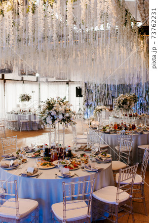The presidium of the newlyweds in the banquet hall of the restaurant is decorated with candles and green plants The presidium of the newlyweds in the banquet hall of the restaurant is decorated with candles and green plants 73762231