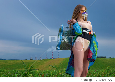Portrait of a young woman with long hair and creative art make-up, in an oxygen mask decorated with flowers 73764155