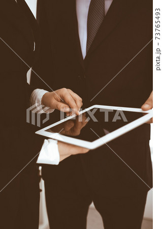 Businessman and woman using tablet computer for discussing questions in office. Partners or colleagues at meeting. Business cooperation concept 73765493