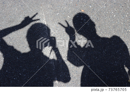 道路でピースをする2人の女性の影の写真素材