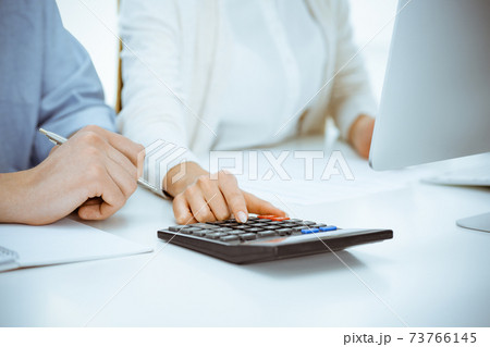 Bookkeeper checking balance with calculator or making finance report, close-up of hands. Tax and audit concepts Bookkeeper checking balance with calculator or making finance report, close-up of hands. Tax and audit concepts 73766145