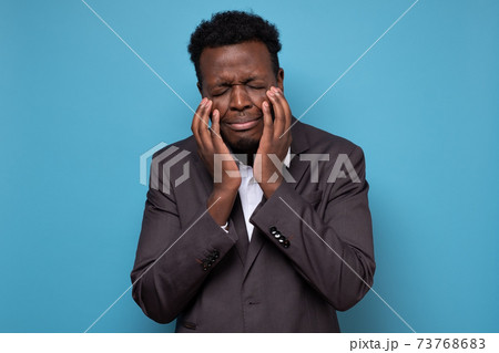 African man in suit being stressed, is going to cry. 73768683